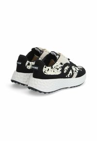 Baskets en daim noir et blanc avec une semelle blanche texturée et surdimensionnée, arborant un motif éclaboussé et une marque bien visible à l'arrière.