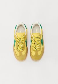 Yellow athletic sneakers with green accents and textured laces. Features a suede and mesh upper, rounded toe, and a gum rubber sole.