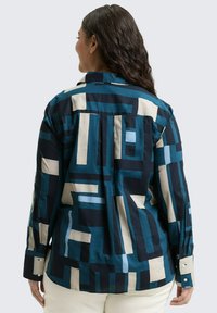 Overhemd met knopen, voorzien van een geometrisch patroon in teal, marineblauw en crème, met lange mouwen en een rugafwerking voor een relaxte pasvorm.