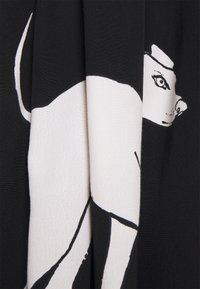 Tela negra con diseño de silueta de perro en blanco y negro. La tela es suave con un acabado ligeramente texturado. Los detalles incluyen características específicas del perro.