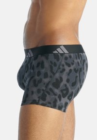 Sportovní trenýrky s černo-šedým leopardím vzorem, s černým elastickým pasem se třemi světle šedými pruhy a těsným střihem.
