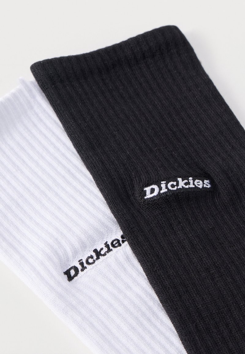Due calze a costine, una nera e una bianca, ciascuna con il logo "Dickies" ricamato vicino al polsino.