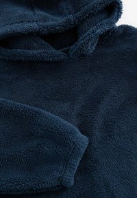 Marinblå fleecehoodie med en mjuk textur, som har en huva och vida ärmar. Tyget har ett lyxigt, inbjudande utseende.