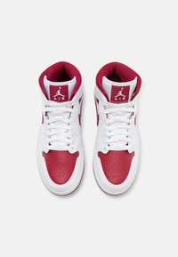Zapatillas altas con parte superior de cuero blanco con detalles en rojo, puntera perforada, cordones blancos y logo de Jordan en la lengüeta.