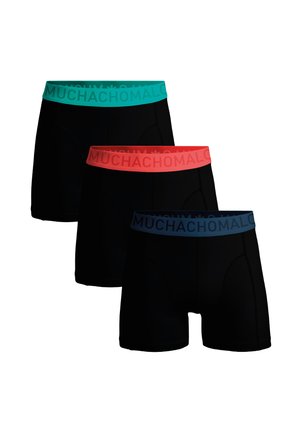 Trīs melnas bokseršortu pāri ar krāsainām elastīgām jostām; augšējajām ir tirkīza, vidējām korāla, apakšējām jūras zilas krāsas, visām ir uzraksts "MUCHACHOMALO".