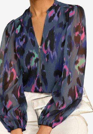 Blusa trasparente di colore blu scuro, con una stampa animale colorata nei toni del viola, rosa e verde, zip frontale e maniche a sbuffo.