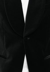 Crna baršunasta sako jakna sa šalom kragnom, jednim dugmetom zatvaranja i dva prednja džepa. Mekana tekstura i elegantan dizajn.