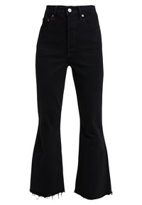 Jeans de mezclilla negra de pierna acampanada con cintura alta, que cuentan con cierre de botón, dobladillo deshilachado y una textura suave.