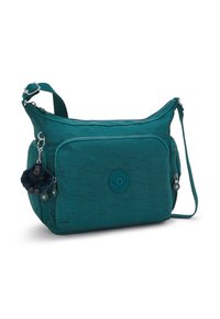 Teal crossbody bag with adjustable strap, multiple zippered compartments, and a small plush monkey keychain attached to the side.