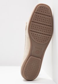 Semelle de chaussure beige avec motif circulaire, trois rainures horizontales, "GEOX" et "Italian Patent" en relief au-dessous.