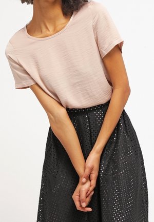 Světle růžový top s krátkými rukávy, hladkou texturou a zaobleným výstřihem, doplněný černou perforovanou sukní s přiléhavým pasem.