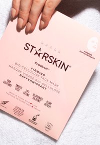 Lys rødt pakket ansigtsmaske med sort tekst; inkluderer ikoner for fordele. Lavet af bio-cellulose, infunderet med serum baseret på kokos.