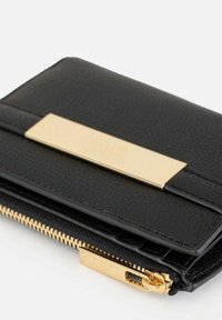 Portafoglio in pelle nera con dettaglio in metallo dorato, con chiusura a zip nella parte inferiore e texture liscia. Forma compatta e rettangolare.