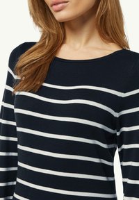 Navyblaues Langarmoberteil mit horizontalen weißen Streifen, Rundhalsausschnitt und strukturiertem Strickstoff, der eine lockere Passform betont.