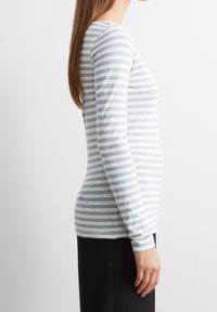 Maglia a maniche lunghe a righe in azzurro chiaro e bianco, con scollatura rotonda e silhouette aderente, realizzata in morbido tessuto jersey di cotone.