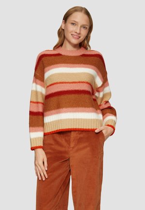 Pull rayé aux teintes chaudes de rouge, beige et rose. Confectionné en tricot texturé avec un ourlet côtelé et de larges manches. Associé à un pantalon en velours côtelé.