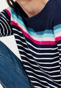 Marineblauwe lange mouwen shirt met horizontale strepen in roze, lichtblauw en wit, met een ronde hals en een ontspannen pasvorm.