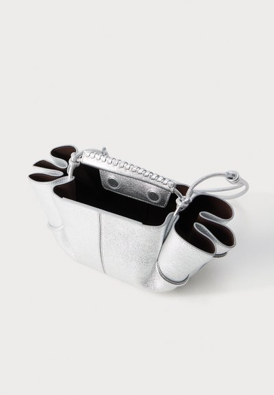 Ασημένια υφασμάτινη τσάντα με ανοιχτό επάνω μέρος, με πλεγμένες και δεμένες λαβές και καμπυλωτές πλευρικές θήκες σε λευκό φόντο.