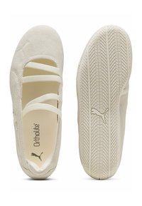 Ballerines Puma beige clair avec trois brides élastiques, semelle en caoutchouc texturée avec logo Puma, et semelle intérieure Ortholite visible.