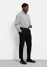 Gray long-sleeve shirt with a button-up design, paired with black trousers and black shoes, featuring a slim fit and tucked appearance.