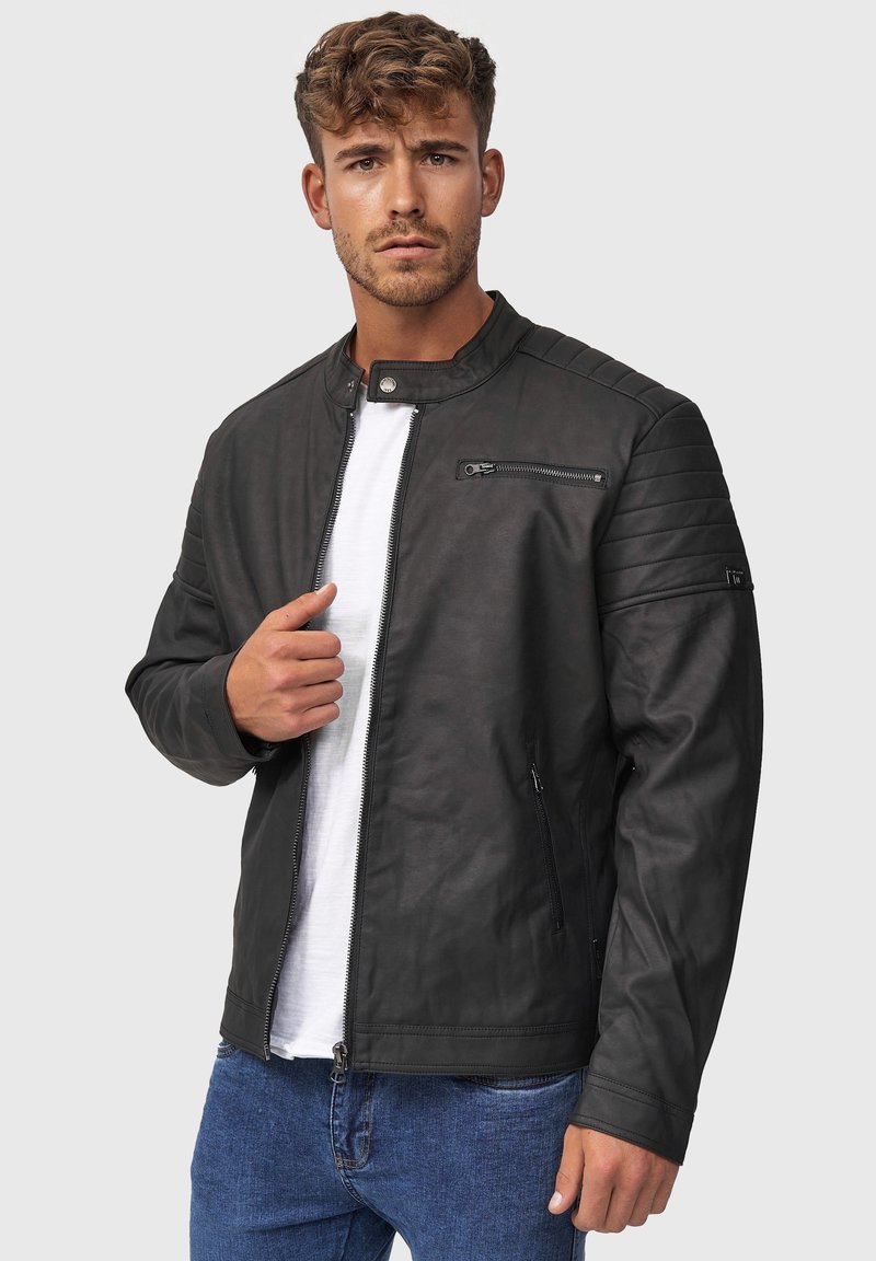 Schwarze Lederjacke mit Stehkragen, schräger Reißverschlusstasche, gesteppten Schulterakzenten und glatter Textur, getragen über einem weißen Hemd.