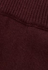 Bordeaux gestrickter Stoff mit einer gerippten Textur an der Oberseite, die feine Stiche und eine glatte, gleichmäßige Oberfläche zeigt.