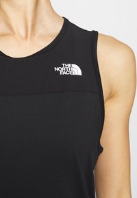 Czarny sportowy top bez rękawów z teksturowaną górną częścią, okrągłym dekoltem i białym logo The North Face na piersi.