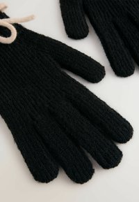 Schwarze gestrickte Handschuhe mit rippenähnlicher Textur und weichem Finish. Akzentuiert mit einem hell gefärbten Band in der Nähe des Handgelenks. Standard Fingerdesign.