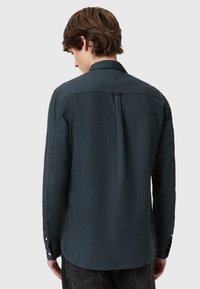 Camicia a maniche lunghe da uomo verde scuro, con colletto button-down, polsini abbottonati e orlo leggermente curvo. Tessuto con trama liscia.