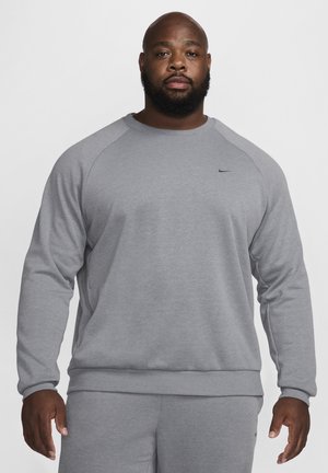 Sweatshirt gris avec des manches raglan, un col rond, une texture douce, et un logo Nike discret sur la poitrine, associé à un pantalon gris assorti.