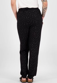Černé kalhoty s rozptýleným vícolorým tečkovaným vzorem, volným střihem, elastickým pasem a zúženými manžetami. Měkká, lehká tkanina.