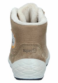 Braune Wildleder-Stiefelette mit einem weichen weißen Futter, ausgestattet mit einem runden Logopatch und einer strukturierten weißen Gummisohle mit Grip.