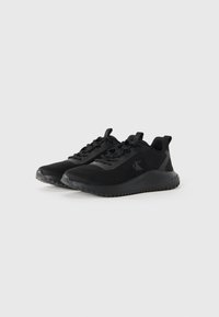 Zwarte atletische schoenen gemaakt van ademend mesh en synthetisch materiaal, met een gestructureerde zool, een gevoerde kraag en een vetersluiting.