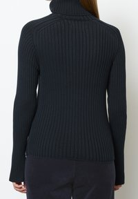 Tumma, poimutettu villapaita korkealla kauluksella, vartalonmyötäinen malli, pitkät hihat ja teksturoitu pinta, jossa hienovaraiset pystysuorat linjat.