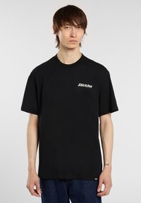 Černé tričko s krátkým rukávem a vroubkovaným kulatým výstřihem, na levé straně hrudi je bílé vyšívané logo. Vyrobeno z měkké bavlny, standardní střih.