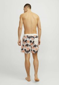 Pantaloni da bagno da uomo con motivo a palme in nero e pesco su sfondo bianco. Presentano un elastico in vita e una tasca sul retro.