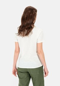 Witte, kortärmsgem t-shirt gemaakt van zacht materiaal, gecombineerd met groene cargo-broek. De achterkant toont een eenvoudig crew neck design.