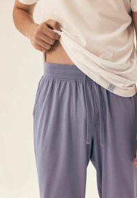 Grey cotton lounge pants with an elastic waistband and drawstring. The fabric appears soft and comfortable, featuring side pockets.