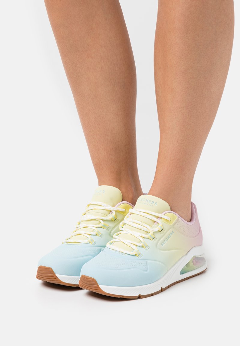 Baskets de sport aux couleurs pastel avec un dessus bleu clair et jaune, semelle intermédiaire blanche et un détail de amortissement à air transparent. Semelle extérieure en caoutchouc striée.