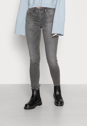 Gray jeans with a slim fit, made of denim. Paired with black Chelsea boots and a light blue cropped sweater featuring wide sleeves.
