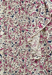 Lichte stoffen jurk met een bloemenprint in roze en marineblauwe details. Rimpellichaam met knopen en gerimpelde randen.