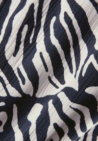 Marineblaues und cremefarbenes Stoffmuster mit Zebra-Design, das abwechselnde Streifen und eine strukturierte Oberfläche mit subtilen Falten aufweist.