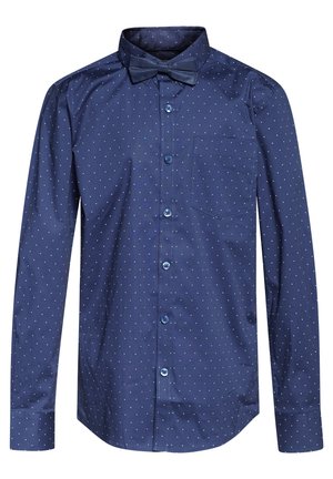 Camisa azul marino de manga larga con lunares blancos, cuello abotonado, un bolsillo delantero y una pajarita a juego. Presenta botones azules.