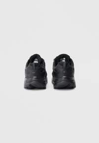 Ténis atléticos pretos com parte superior em malha texturizada, solas almofadadas e detalhes reforçados no calcanhar, vistos de trás.