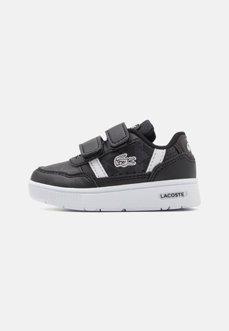 Baskets Lacoste noir et blanc avec deux lanières velcro, panneau latéral texturé et semelle blanche avec logo Lacoste sur le talon.