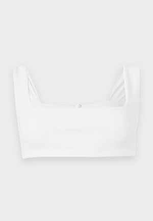 Weißes cropped Tanktop mit breiten Schulterträgern und quadratischem Ausschnitt, flach auf weißem Hintergrund liegend.