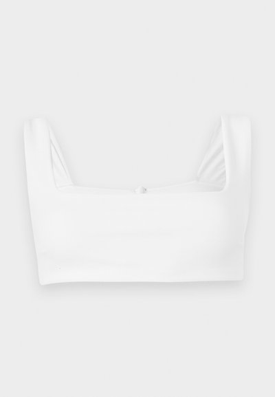 Λευκό κοντό τοπ με φαρδιές τιράντες και τετράγωνο ντεκολτέ, απλωμένο επίπεδα σε λευκό φόντο.