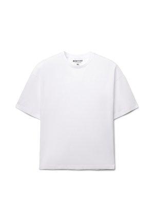 T-shirt bianca a taglio quadrato con maniche corte, scollo rotondo e texture morbida. L'etichetta indica la taglia XL. Design minimalista, senza motivi o accenti.