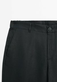 Black trousers made of a structured fabric. Features include a flat front, side pockets, belt loops, and a button closure.