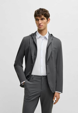 Gray zip-up blazer with a hood, featuring a tailored fit and front pocket, layered over a white collared shirt and matching gray pants.